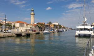 ヴォヴェールにあるGîte de vacances en Camargue ☆☆NNの時計塔のある町に停泊する船の川