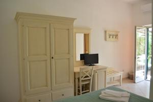 a bedroom with a bed and a desk with a television at Agrialbergo Capalbio in Capalbio