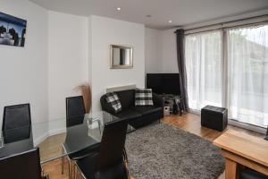 een woonkamer met een zwarte bank en een tafel bij Parc y Bryn Serviced Apartments in Aberystwyth