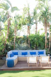 a blue couch and two chairs on a deck with palm trees at Holiday House Palm Springs in Palm Springs
