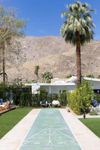 a house with a palm tree and a tennis court at Holiday House Palm Springs in Palm Springs