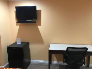 Una habitación con un escritorio y un televisor en la pared. en Executive Suites Inn, en Westminster 8 fotos más