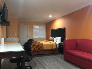 Executive Suites Inn في ويستمنستر: غرفة فندق بسرير واريكة حمراء