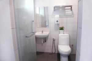 a white bathroom with a toilet and a sink at Brezza Hotel Sitiawan in Sitiawan