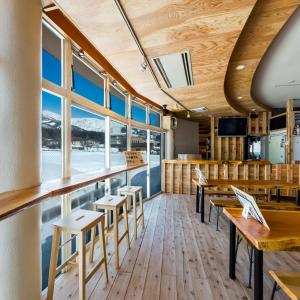 a restaurant with tables and chairs and windows at Hakuba Panorama Hotel in Hakuba