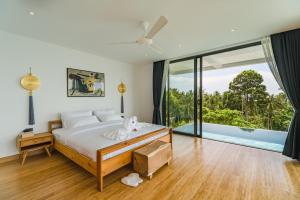 a bedroom with a bed and a large window at Villa Tosti in Ban Bang Po