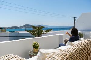 a woman sitting on a balcony looking out at the ocean at Korali Boutique Hotel in Naxos Chora