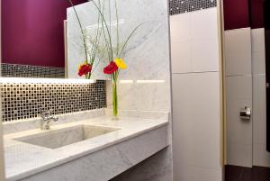 a bathroom with a sink with a vase of flowers at Kube Apartments Express in Córdoba +28 photos