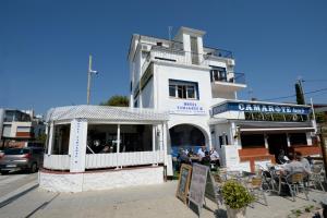 a white building with people sitting outside of it at Hotel Beach Playa in Castelldefels