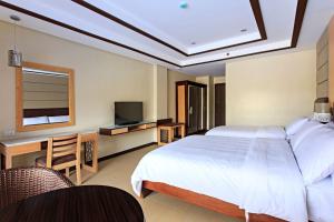 Dormitorio con cama, escritorio y TV en Cebu Westown Lagoon - South Wing, en Cebú