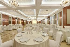 a banquet hall with white tables and chairs and chandeliers at Golden Ring Resort in Tirana