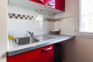a kitchen with a sink and a red cabinet at Cosy appart proche Paris in Saint-Denis