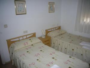 - une chambre avec 2 lits avec des fleurs roses sur les draps dans l'établissement Ocean 3 - Fincas Arena, à Benidorm