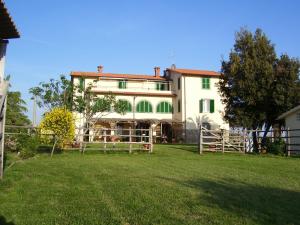 una casa bianca con una recinzione di fronte a un cortile di Casale Sant'Angelo a Capalbio