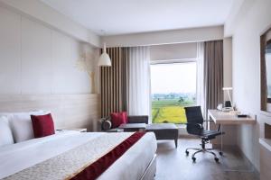 a hotel room with a bed and a desk and a window at Oaks Bodhgaya in Bodh Gaya