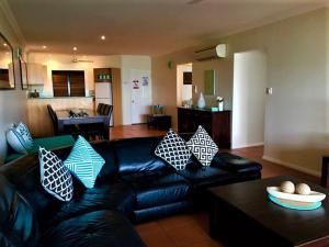 a living room with a black leather couch with pillows at Compass Point 8 in Hamilton Island