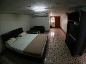 PuengLuang Hotel في دامنون سادواك: غرفة نوم بسرير وتلفزيون بشاشة مسطحة