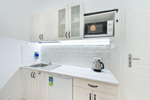a kitchen with white cabinets and a microwave at YOURAPART Chlebnicka in Gdańsk
