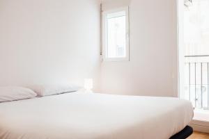 Cama blanca en habitación blanca con ventana en Botànic Apartaments, en Valencia
