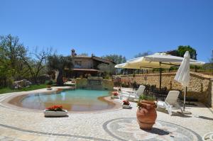 a swimming pool with an umbrella and chairs and a table and an umbrella at Agriturismo Le Faeta in Arpino