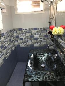 a bathroom with a black sink and blue and white tiles at Aerizo bungalow & Tours in Nuwara Eliya