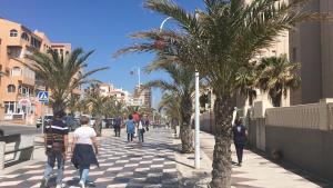 un grupo de personas caminando por una acera con palmeras en Apartamentos Arenales Del Sol III, en Arenales del Sol