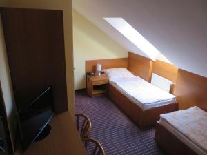 una camera d'albergo con due letti e una TV a schermo piatto di Hotel Arnold a Tata