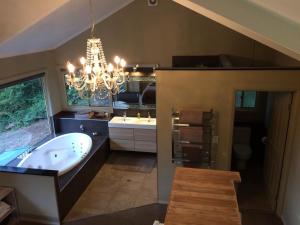 un ampio bagno con vasca e lampadario a braccio di Maleny Luxury Cottages a Maleny