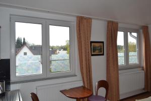 a room with three windows and a table and chairs at Apartotel Köln Frechen in Frechen