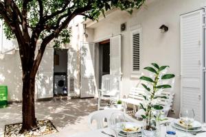 a table with white chairs and a tree on a patio at DELPOSTO Marina di Ragusa (az) in Marina di Ragusa