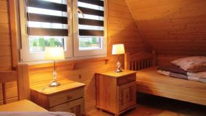 1 dormitorio con 2 lámparas y 1 cama en una cabaña en Bajkowe Domki en Polańczyk