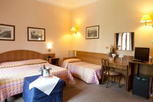 Pokój hotelowy z 2 łóżkami i biurkiem w obiekcie Hotel Porziuncola w Asyżu