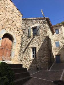 un antiguo edificio de piedra con una puerta de madera y escaleras en Maison Ancienne Minervois, en La Caunette