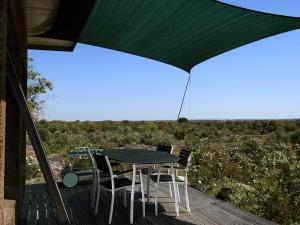 a patio with a table and chairs on a deck at Bubulcus and Bolotas - Off Grid Nature Holiday Home in Vimieiro