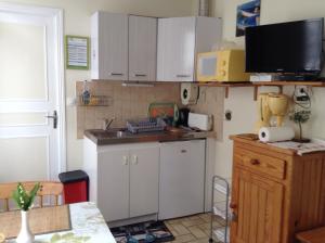 een kleine keuken met witte kasten en een wastafel bij Au Bon Gite - Studio in Arromanches-les-Bains