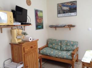 a living room with a couch and a television at Au Bon Gite - Studio in Arromanches-les-Bains