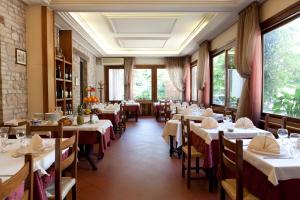uma sala de jantar com mesas, cadeiras e janelas em Hotel Porziuncola em Assisi