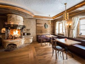 ペルティサウにあるHotel Alpenroseの暖炉、テーブル、椅子が備わるレストラン
