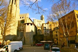 a church with cars parked in front of a street at La Lleona Apartment in Girona