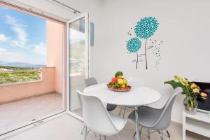 a white dining room with a table and chairs and a window at Panorama Holidays in Kaštela