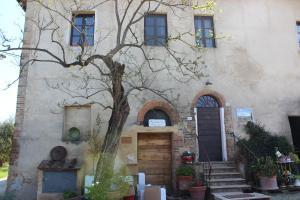 dom z drzewem przed nim w obiekcie Bio Agriturismo Podere Pretoia w mieście San Gimignano