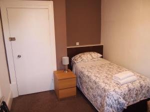 a small bedroom with a bed and a night stand at Kingswood Hotel in Maidenhead