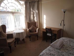 a hotel room with a bed and chairs and a window at Kingswood Hotel in Maidenhead