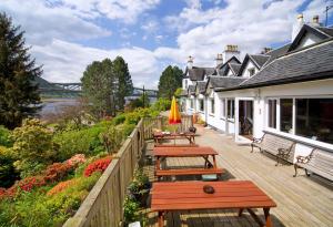 a row of wooden benches on a wooden deck at Loch Leven Hotel & Distillery in Glencoe