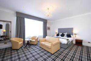 um quarto de hotel com uma cama e cadeiras e um lustre em The Royal George Hotel em Perth
