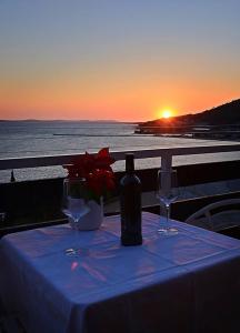 una mesa con dos copas de vino, una botella y una puesta de sol en Cosy Sunset Apartment en Omiš