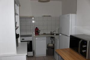 a white kitchen with a sink and a refrigerator at maison de bourg in Talmont