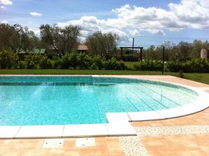 a large swimming pool in a yard with a playground at Agriturismo Il Giglio di S. Antonio in Montemassi