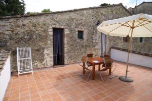 eine Terrasse mit einem Sonnenschirm, einem Tisch und Stühlen in der Unterkunft Casa Vacanze Good Buy in San Gimignano