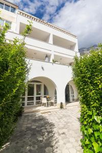 a white building with a patio and a table at Apartments Villa Mili in Brela